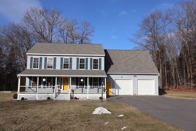 colonial inspired home with a porch, a front lawn, and a garage