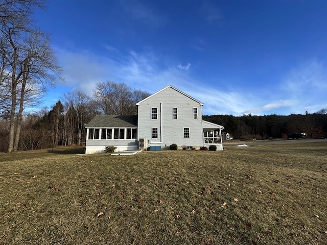 back of property featuring a lawn and a sunroom