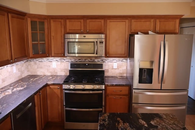 kitchen with glass insert cabinets, brown cabinetry, dark stone counters, and stainless steel appliances