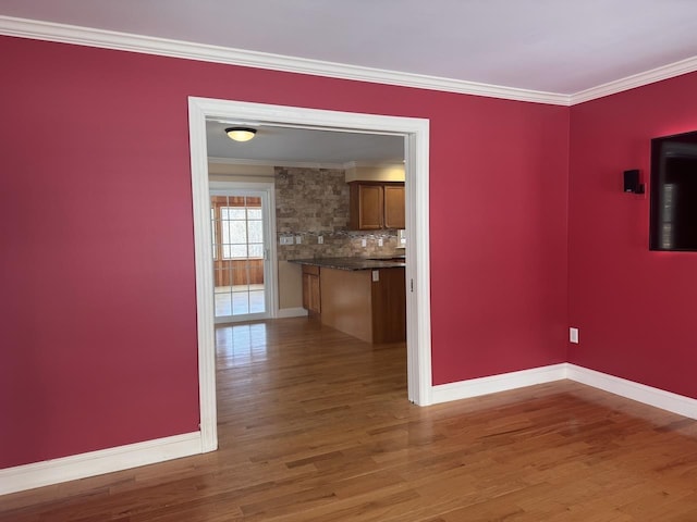 interior space with ornamental molding, baseboards, and wood finished floors