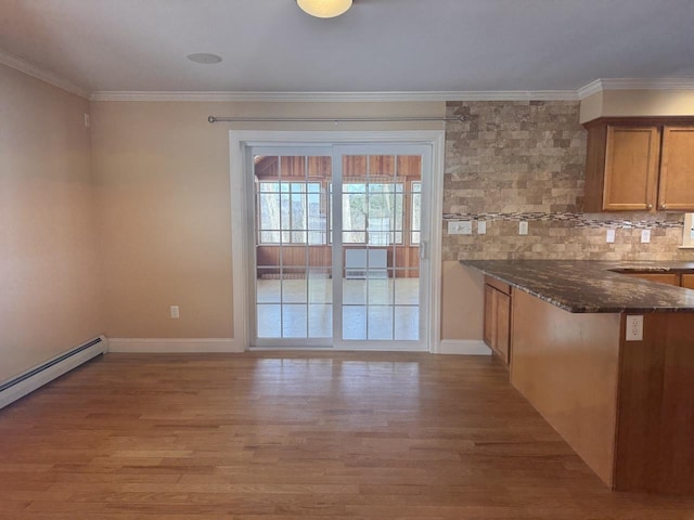 interior space featuring ornamental molding, baseboard heating, baseboards, and light wood finished floors