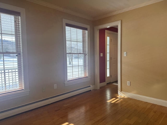 spare room featuring wood-type flooring, ornamental molding, baseboard heating, and baseboards