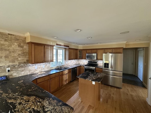 kitchen with stainless steel appliances, dark wood-style flooring, a sink, decorative backsplash, and dark stone countertops