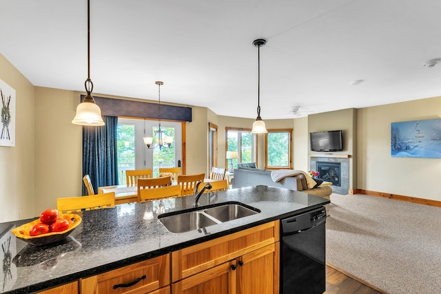 kitchen with sink, black dishwasher, hanging light fixtures, and a tiled fireplace