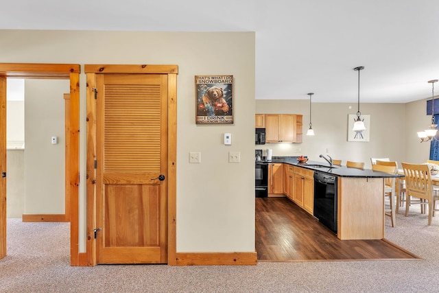 kitchen with pendant lighting, black appliances, dark colored carpet, light brown cabinetry, and a breakfast bar area