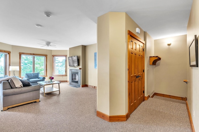 carpeted living room featuring a tile fireplace and ceiling fan