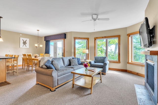 carpeted living room with a tile fireplace, ceiling fan with notable chandelier, and a healthy amount of sunlight