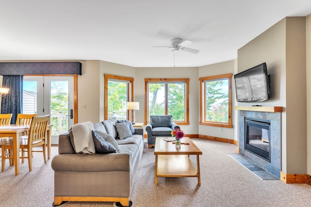 carpeted living room with a tile fireplace and ceiling fan