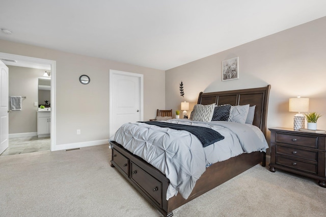 bedroom featuring ensuite bathroom and light colored carpet