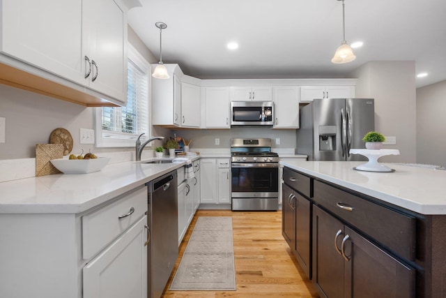 kitchen with pendant lighting, stainless steel appliances, white cabinetry, and sink