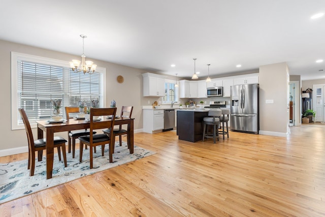 dining area with a healthy amount of sunlight, light hardwood / wood-style floors, and a chandelier