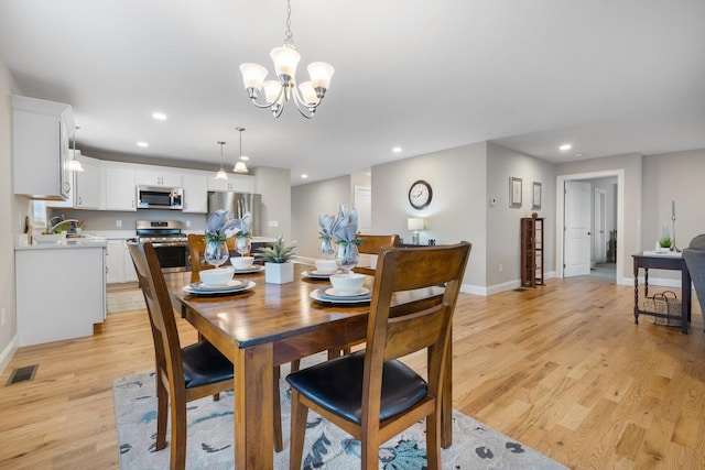 dining room with sink, light hardwood / wood-style flooring, and an inviting chandelier