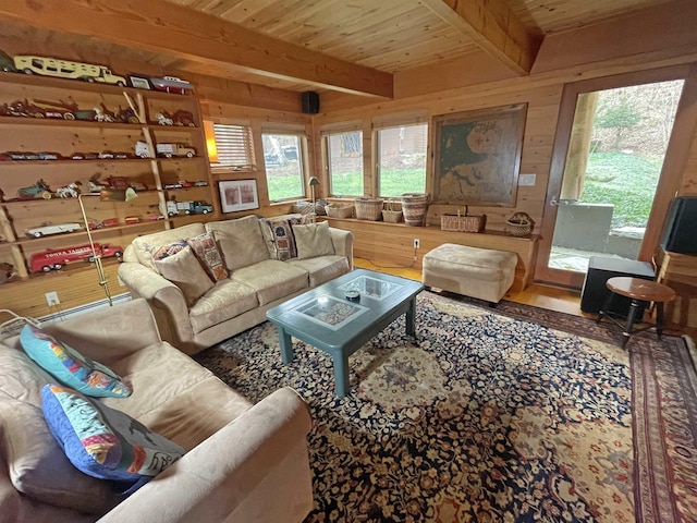 living room featuring beam ceiling, wood walls, and plenty of natural light