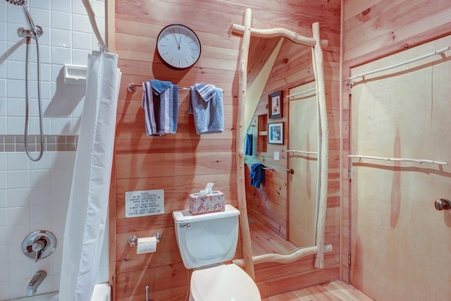 bathroom featuring wood walls and toilet