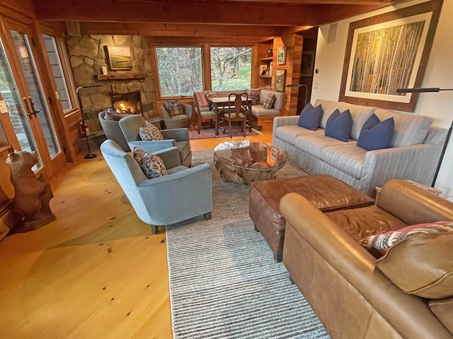 living room with beamed ceiling, french doors, and a stone fireplace