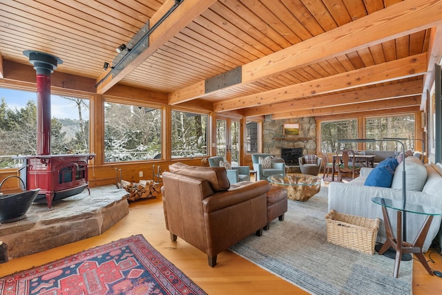 sunroom / solarium featuring beam ceiling, track lighting, and a wood stove