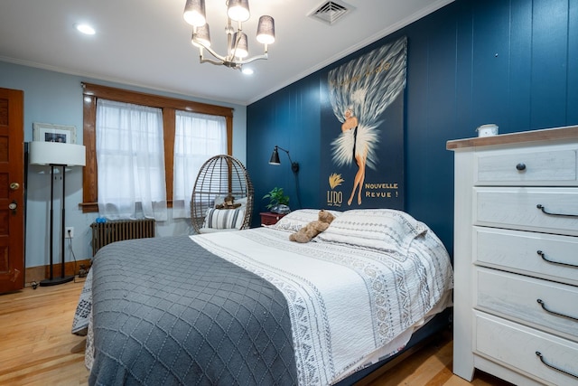 bedroom featuring light hardwood / wood-style floors, radiator, crown molding, and a notable chandelier