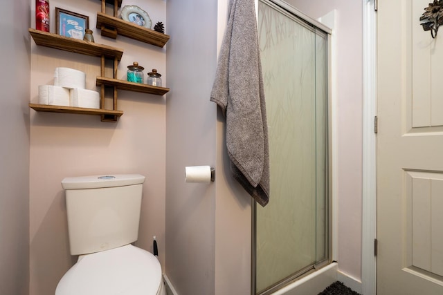 bathroom featuring a shower with shower door and toilet