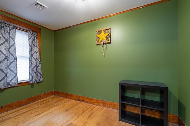 empty room with light wood-type flooring and crown molding