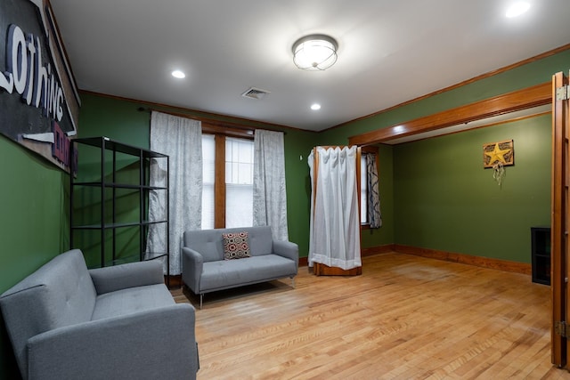 living area featuring crown molding and light hardwood / wood-style flooring