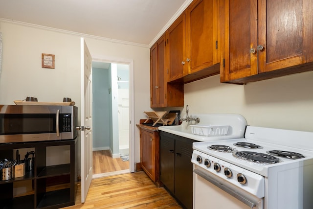 kitchen with white electric range oven, light wood-type flooring, and ornamental molding