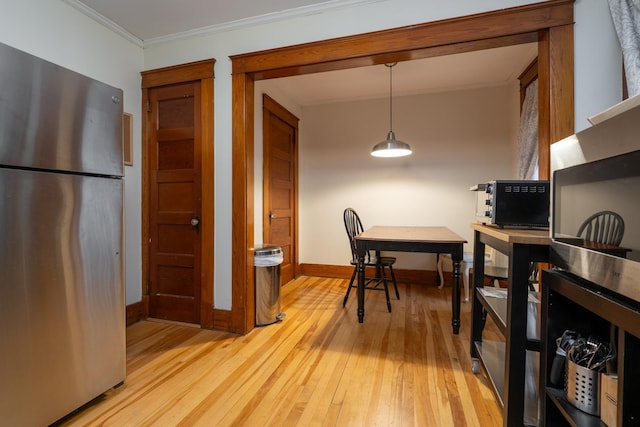 dining space with crown molding and light hardwood / wood-style floors