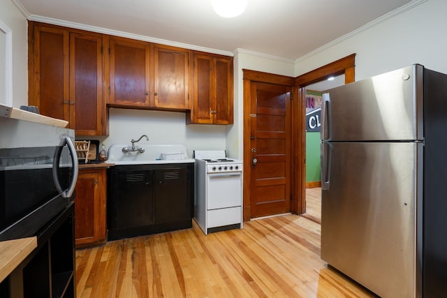 kitchen with white range, ornamental molding, sink, and stainless steel refrigerator