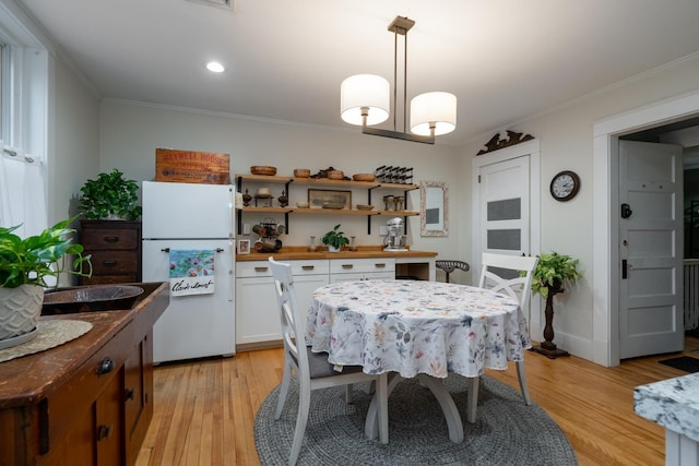 dining area with crown molding and light hardwood / wood-style floors