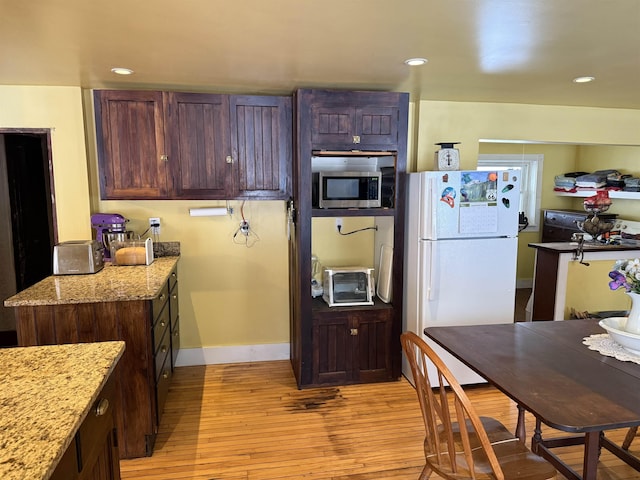 kitchen featuring light stone countertops, light wood-type flooring, and white refrigerator