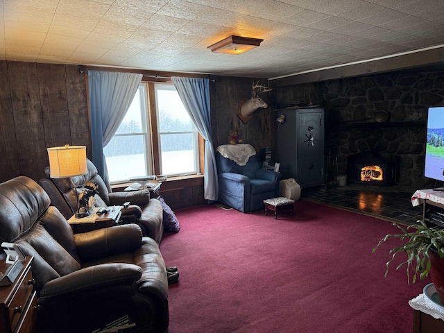 living room featuring carpet flooring, a stone fireplace, and wood walls