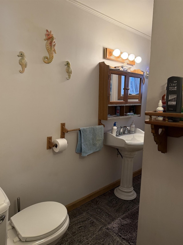 bathroom featuring toilet, ornamental molding, and sink