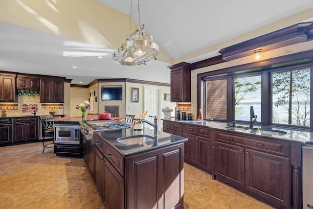 kitchen featuring stainless steel microwave, tasteful backsplash, lofted ceiling, pendant lighting, and sink