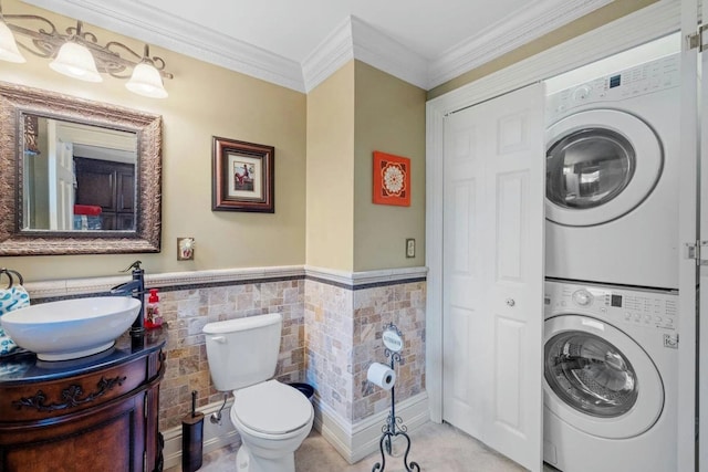 interior space featuring tile walls, stacked washer and dryer, sink, and ornamental molding