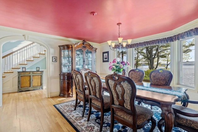 dining area with light hardwood / wood-style floors, crown molding, and an inviting chandelier