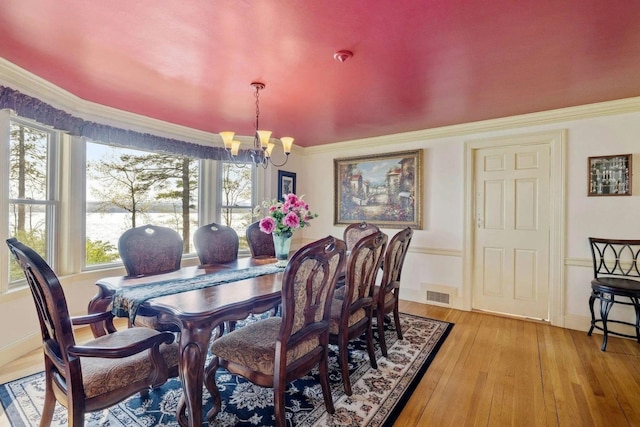 dining space featuring crown molding, a chandelier, and light hardwood / wood-style floors