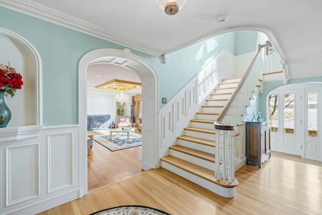 foyer entrance with crown molding and light wood-type flooring