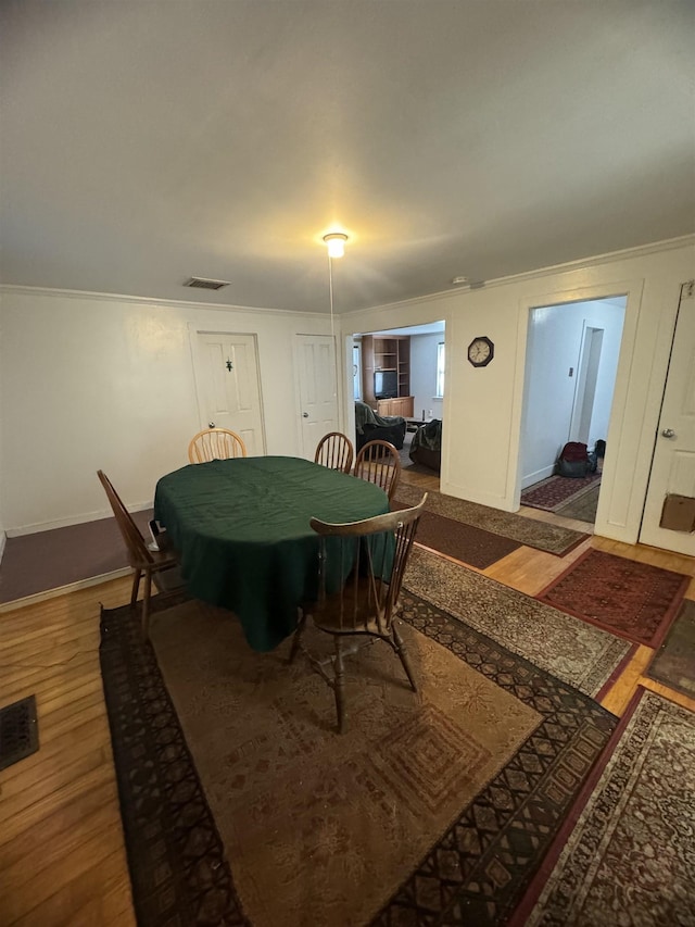 dining area featuring ornamental molding and hardwood / wood-style flooring