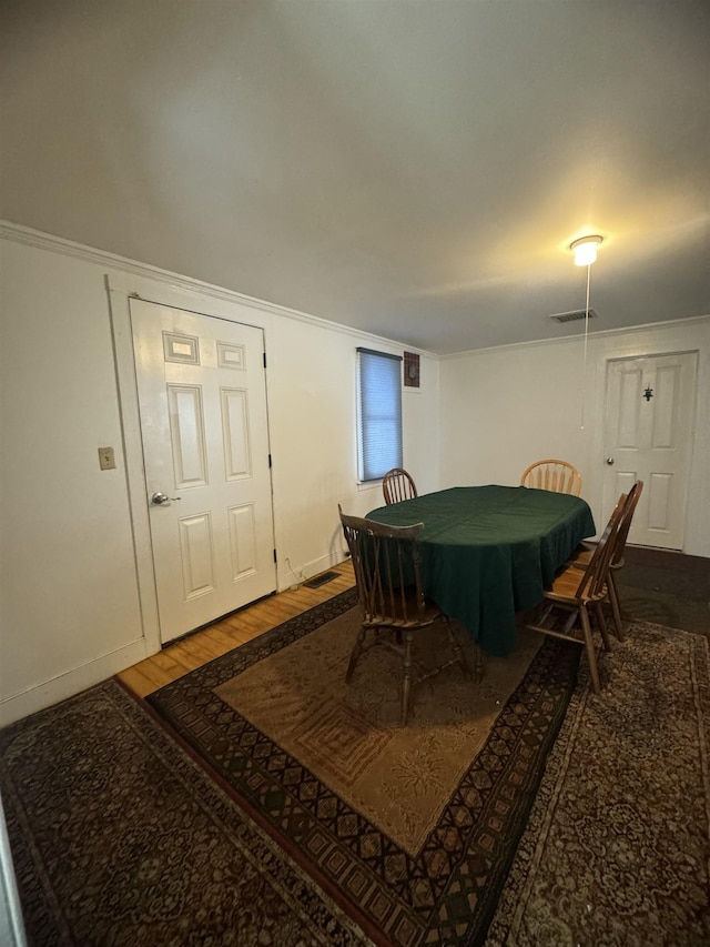 dining area featuring hardwood / wood-style flooring and crown molding