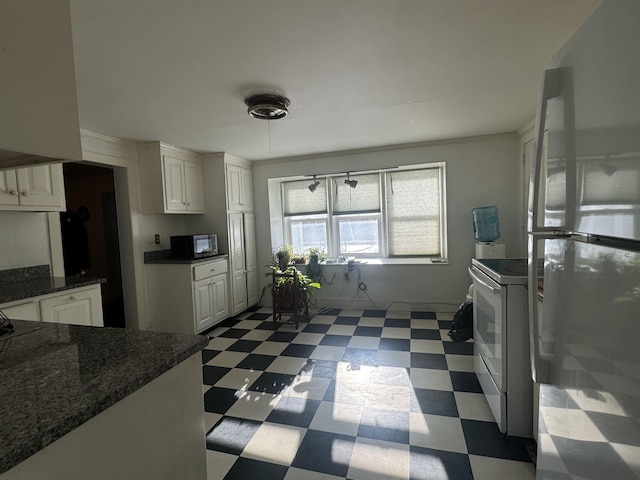 kitchen featuring white range, white cabinets, and fridge