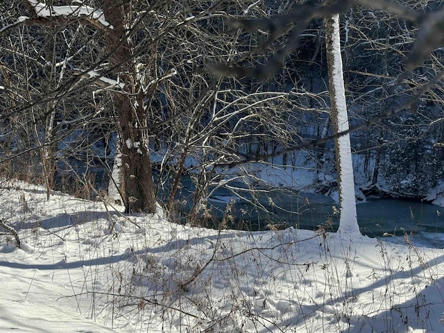 view of snow covered land with a water view