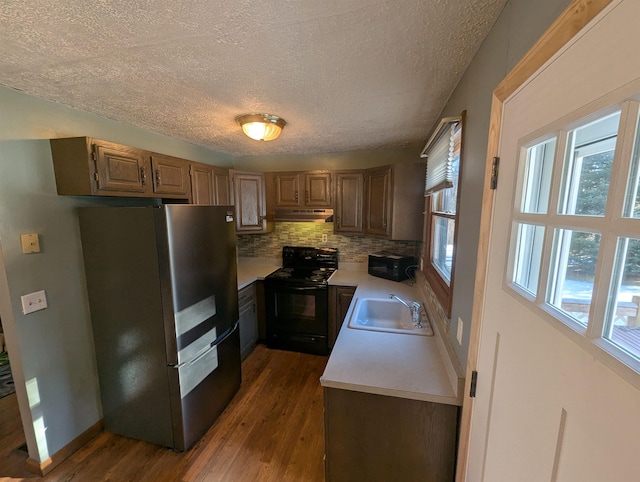 kitchen with sink, tasteful backsplash, dark hardwood / wood-style flooring, black / electric stove, and stainless steel fridge