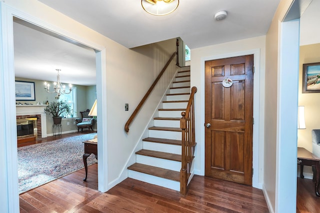 stairway with wood-type flooring and an inviting chandelier