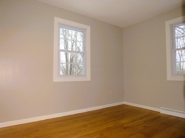 empty room with hardwood / wood-style flooring and plenty of natural light