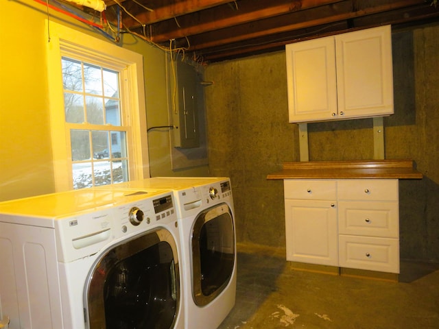 laundry area with electric panel, a wealth of natural light, washer and clothes dryer, and cabinets