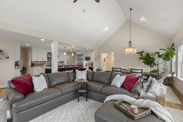 living room with ceiling fan, high vaulted ceiling, and light hardwood / wood-style floors