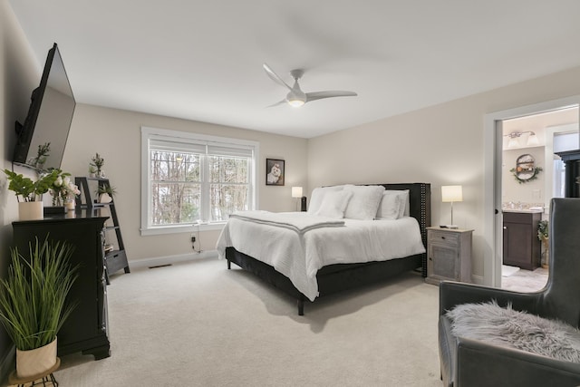 bedroom with connected bathroom, light colored carpet, and ceiling fan