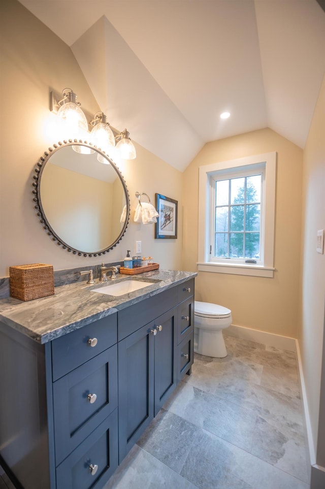 bathroom with lofted ceiling, toilet, and vanity