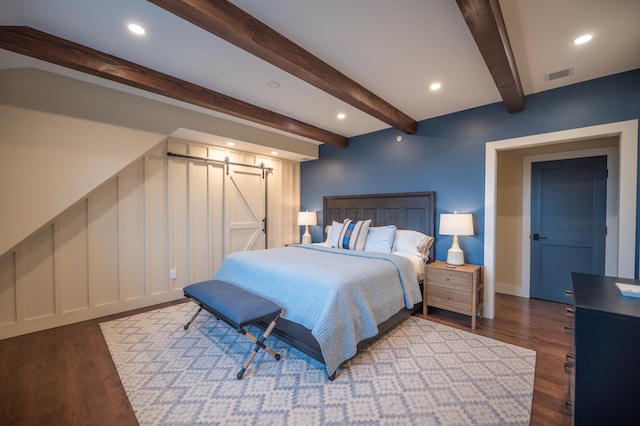 bedroom with dark hardwood / wood-style flooring, a barn door, and beam ceiling