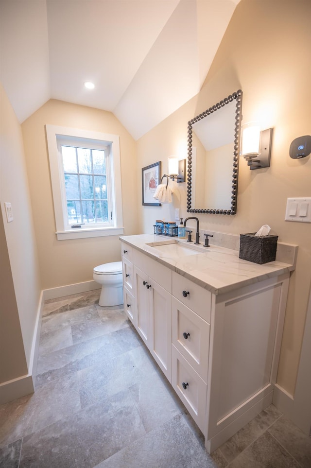 bathroom with vaulted ceiling, vanity, and toilet