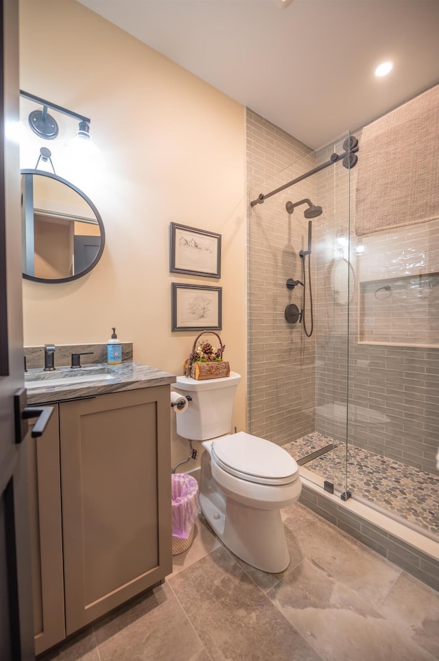 bathroom with a shower with door, vanity, and toilet